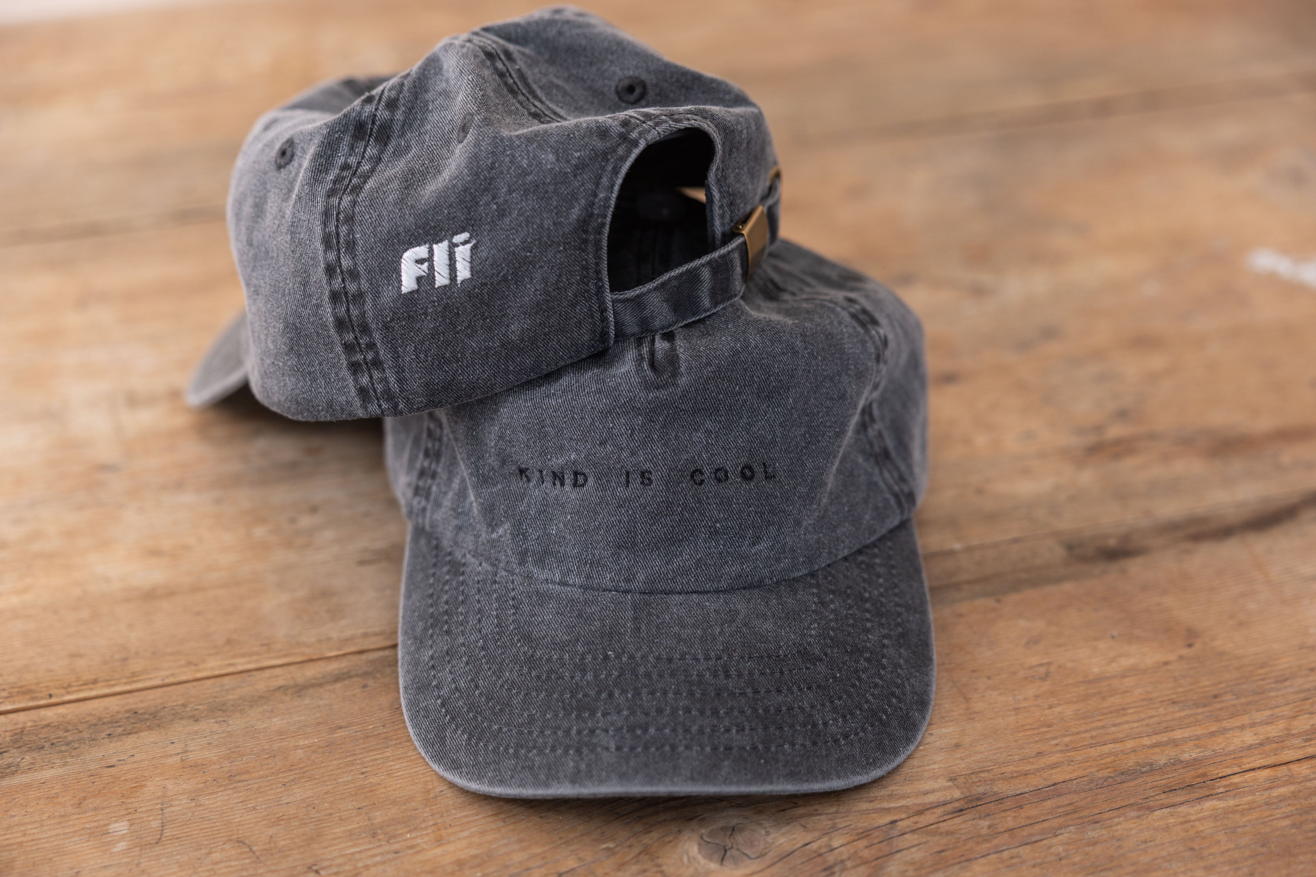 Two gray caps on a wooden surface with 'Fii' branding.