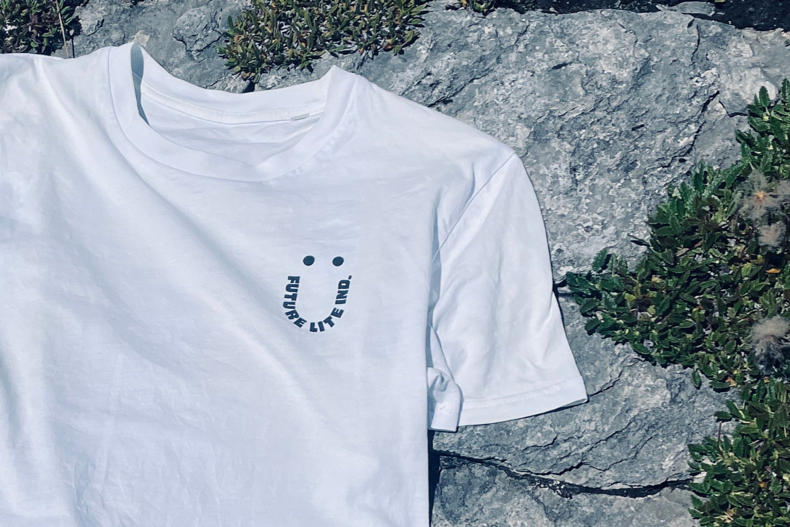 White t-shirt with a smile logo on a rock background
