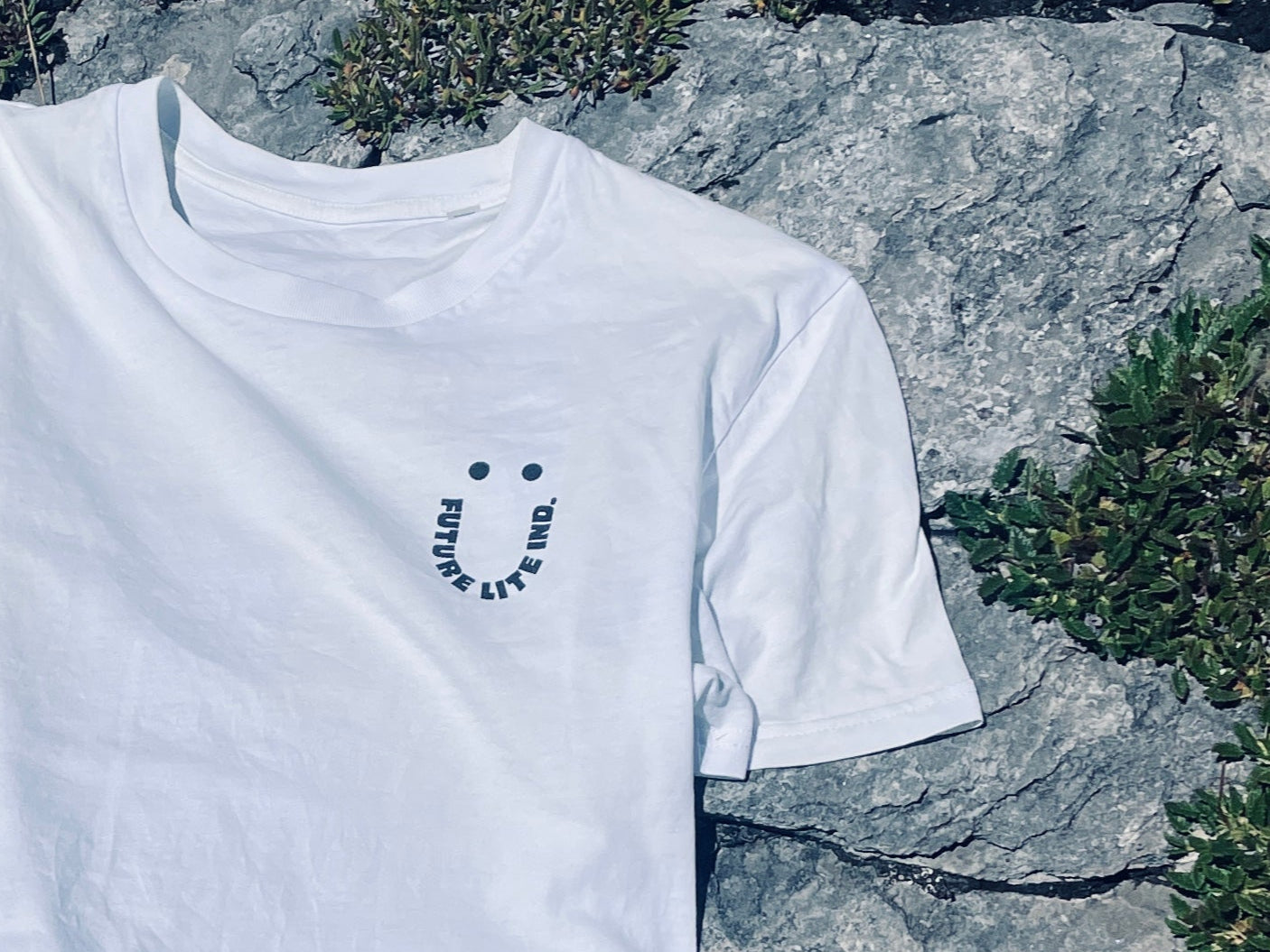 White t-shirt with a smile logo on a rock background