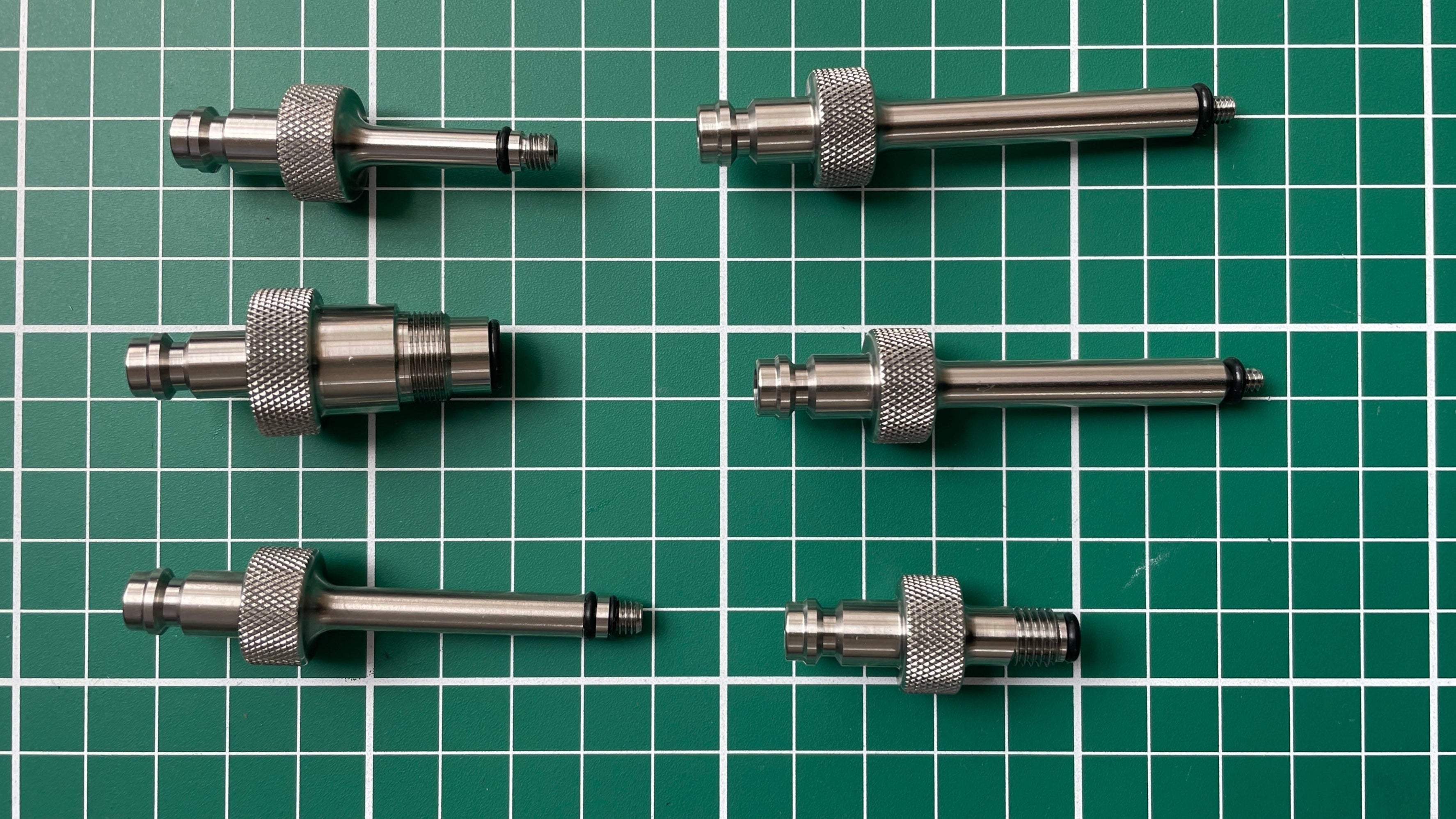 FLI Bleeding adapter: Set of six metal cylindrical components on a green grid background