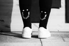 Rear view of legs wearing black MTB socks designed with a smiley face visible to the person behind.