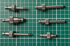 FLI Bleeding adapter: Set of six stainless steel components on a green grid background