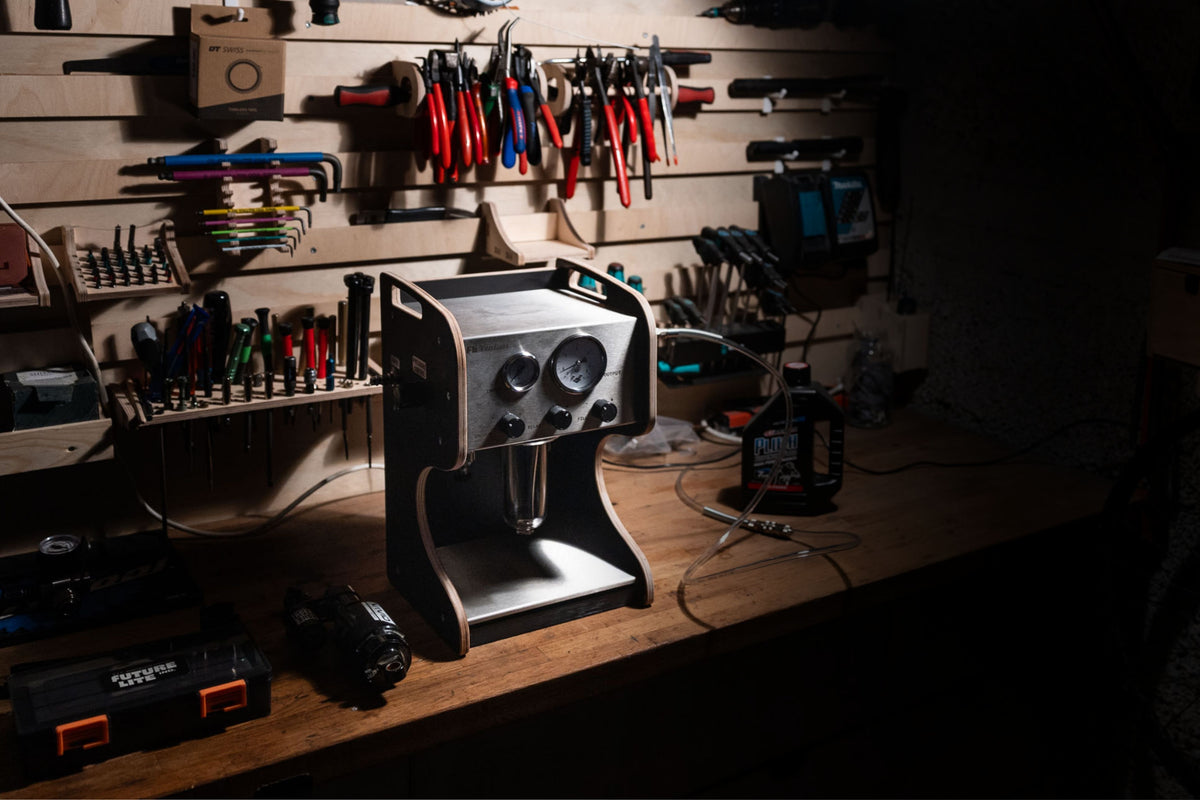Workbench with tools and equipment in shining a light on a Vacuum Pump that looks like a coffee machine.
