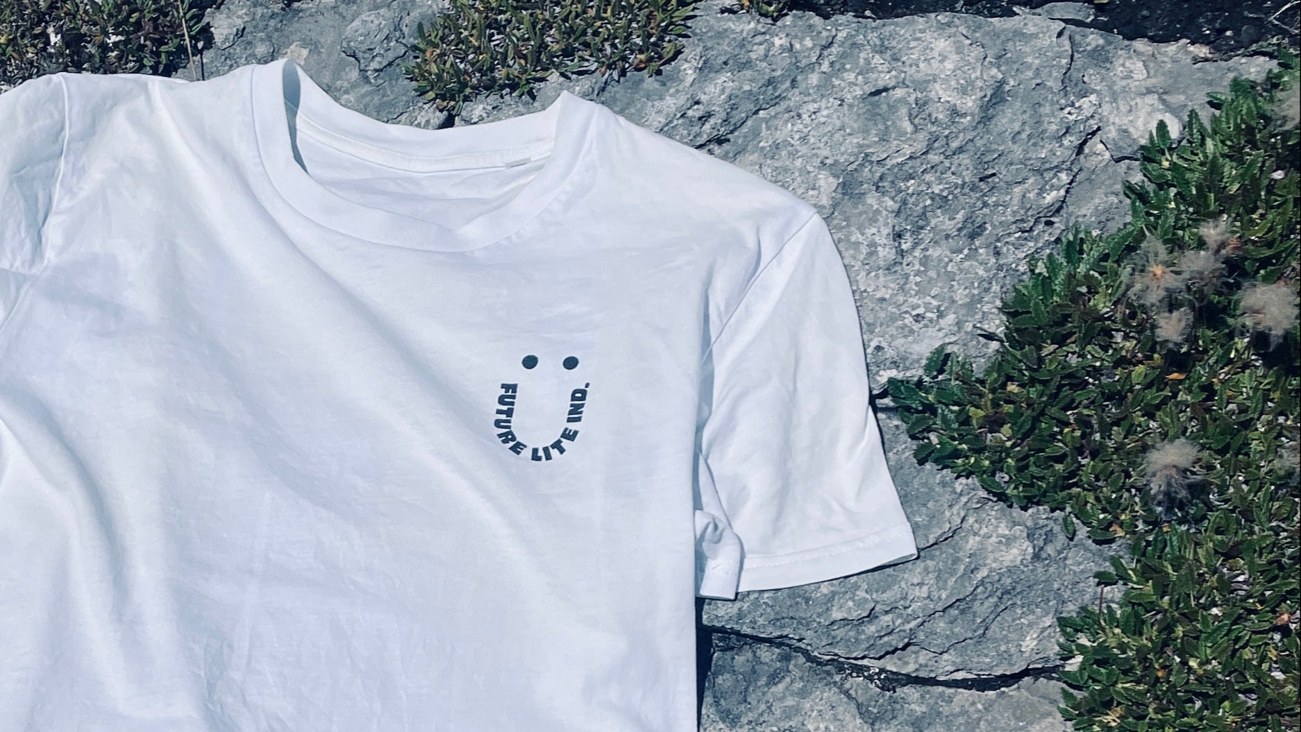 White t-shirt with a smile logo on a rock background